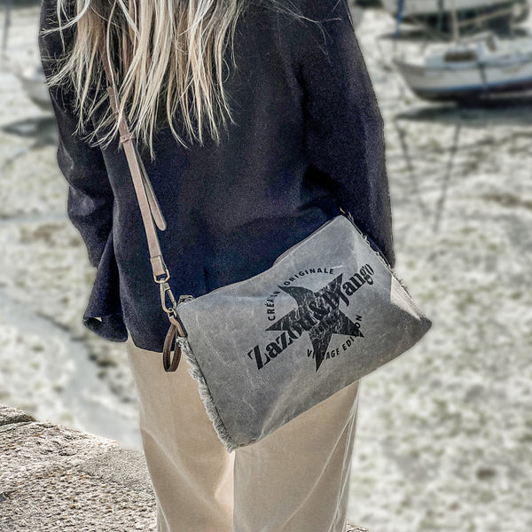 vue taille réelle, porté par mannequin, sur l'épaule. Sac pochette zazou et django, marque française. Bandoulière en cuir vegan amovible et réglable. Toile de coton doublée, fermeture zippée. Mousquetons de chaque côté. Finition en laiton. Peut se porter à la main, en bandoulière ou à l'épaule. Sac à main, trousse de maquillage/de toilette, pour la plage, porte monnaie, trousse à vernis. Parfait pour tous les jours, le boulot, la plage, les vacances, le weekend.