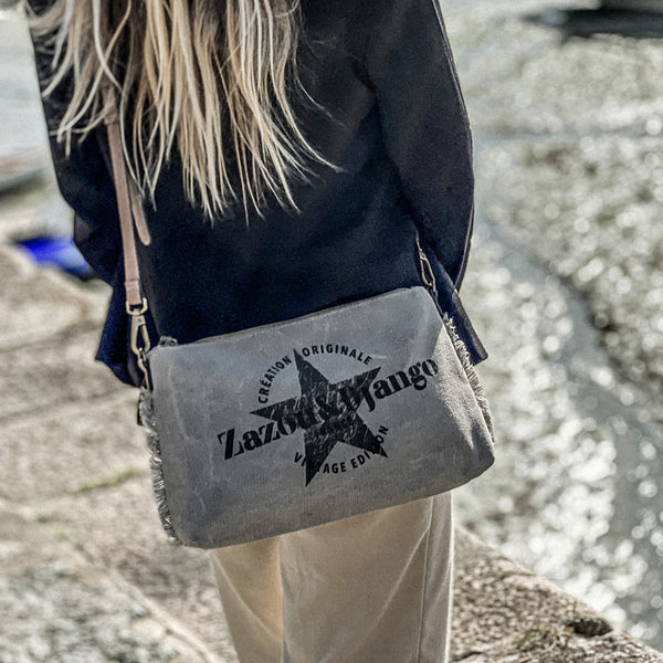 vue taille réelle, porté par mannequin, sur l'épaule. Sac pochette zazou et django, marque française. Bandoulière en cuir vegan amovible et réglable. Toile de coton doublée, fermeture zippée. Mousquetons de chaque côté. Finition en laiton. Peut se porter à la main, en bandoulière ou à l'épaule. Sac à main, trousse de maquillage/de toilette, pour la plage, porte monnaie, trousse à vernis. Parfait pour tous les jours, le boulot, la plage, les vacances, le weekend.