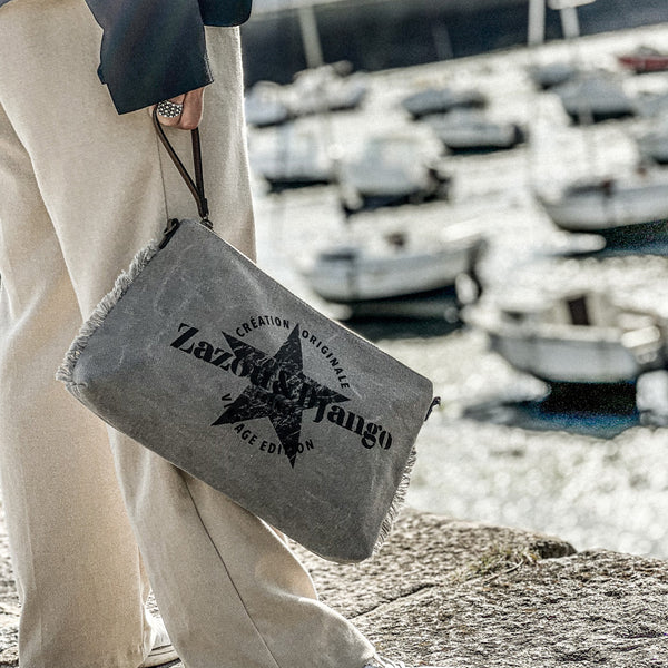 vue taille réelle, porté par mannequin, avec le cordon en cuir vegan. Sac pochette zazou et django, marque française. Bandoulière en cuir vegan amovible et réglable. Toile de coton doublée, fermeture zippée. Mousquetons de chaque côté. Finition en laiton. Peut se porter à la main, en bandoulière ou à l'épaule. Sac à main, trousse de maquillage/de toilette, pour la plage, porte monnaie, trousse à vernis. Parfait pour tous les jours, le boulot, la plage, les vacances, le weekend.