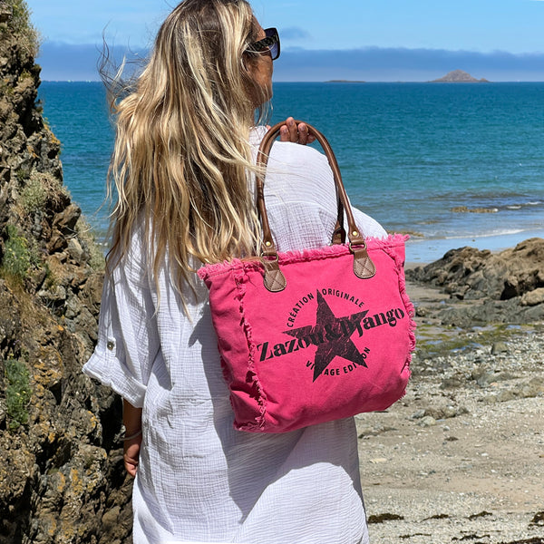 vue taille réelle, porté par mannequin, sac mini cabas quotidien couleur rose fuchsia, girly, pétillant, fluo, rose bonbon, framboise, vif. Toile doublée en coton, détails laitons et cuir vegan. Style décontracté, vintage, froufrous, plage, été. Design original zazou & django.