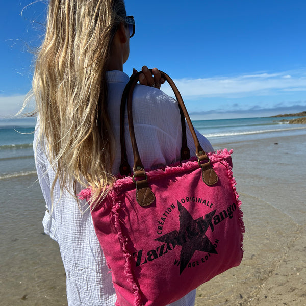 vue taille réelle, porté par mannequin, sac mini cabas quotidien couleur rose fuchsia, girly, pétillant, fluo, rose bonbon, framboise, vif. Toile doublée en coton, détails laitons et cuir vegan. Style décontracté, vintage, froufrous, plage, été. Design original zazou & django.